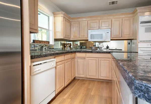 a kitchen with granite countertop white cabinets and white appliances