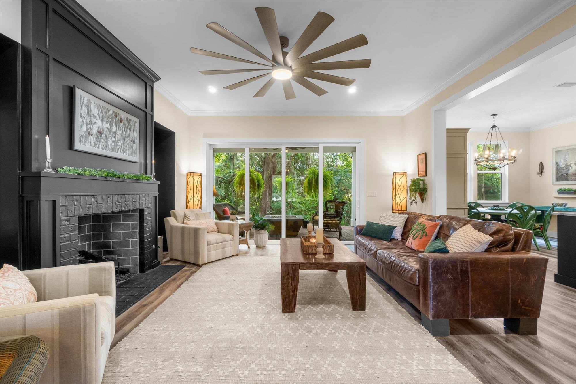 29318 Grandview Manor Yulee, FL 32097 - Photo 13 of 68 Living room with wood finished floors, crown molding, a fireplace with flush hearth, a chandelier, and healthy amount of natural light