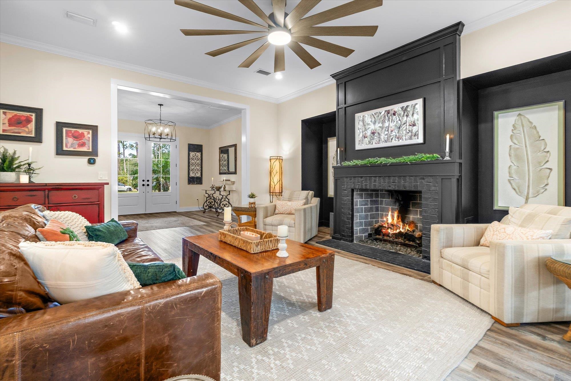 29318 Grandview Manor Yulee, FL 32097 - Photo 14 of 68 Living area with wood finished floors, crown molding, french doors, a fireplace, and a chandelier
