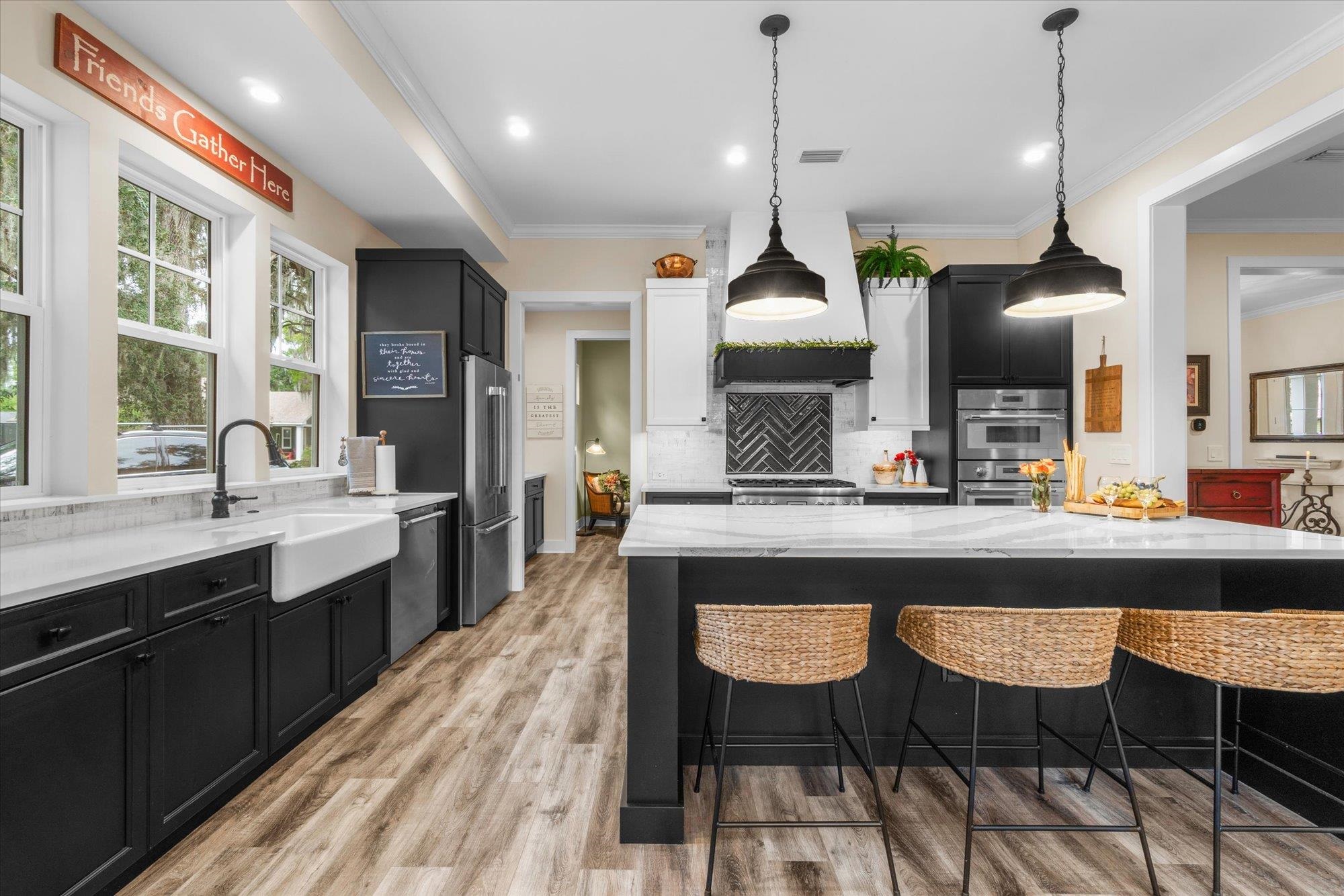 29318 Grandview Manor Yulee, FL 32097 - Photo 18 of 68 Kitchen featuring dark cabinetry, crown molding, a breakfast bar, pendant lighting, and light stone countertops