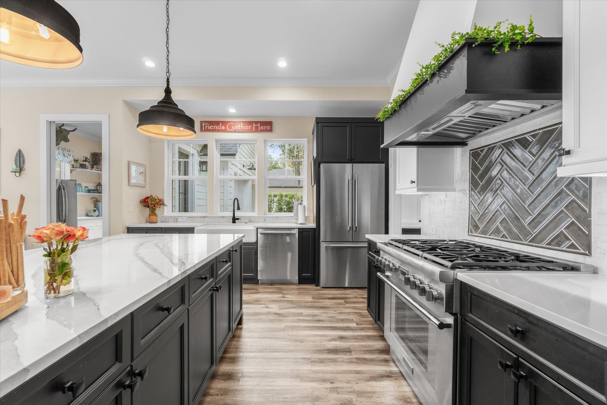 29318 Grandview Manor Yulee, FL 32097 - Photo 4 of 68 Kitchen with premium appliances, decorative backsplash, dark cabinets, ornamental molding, and custom exhaust hood