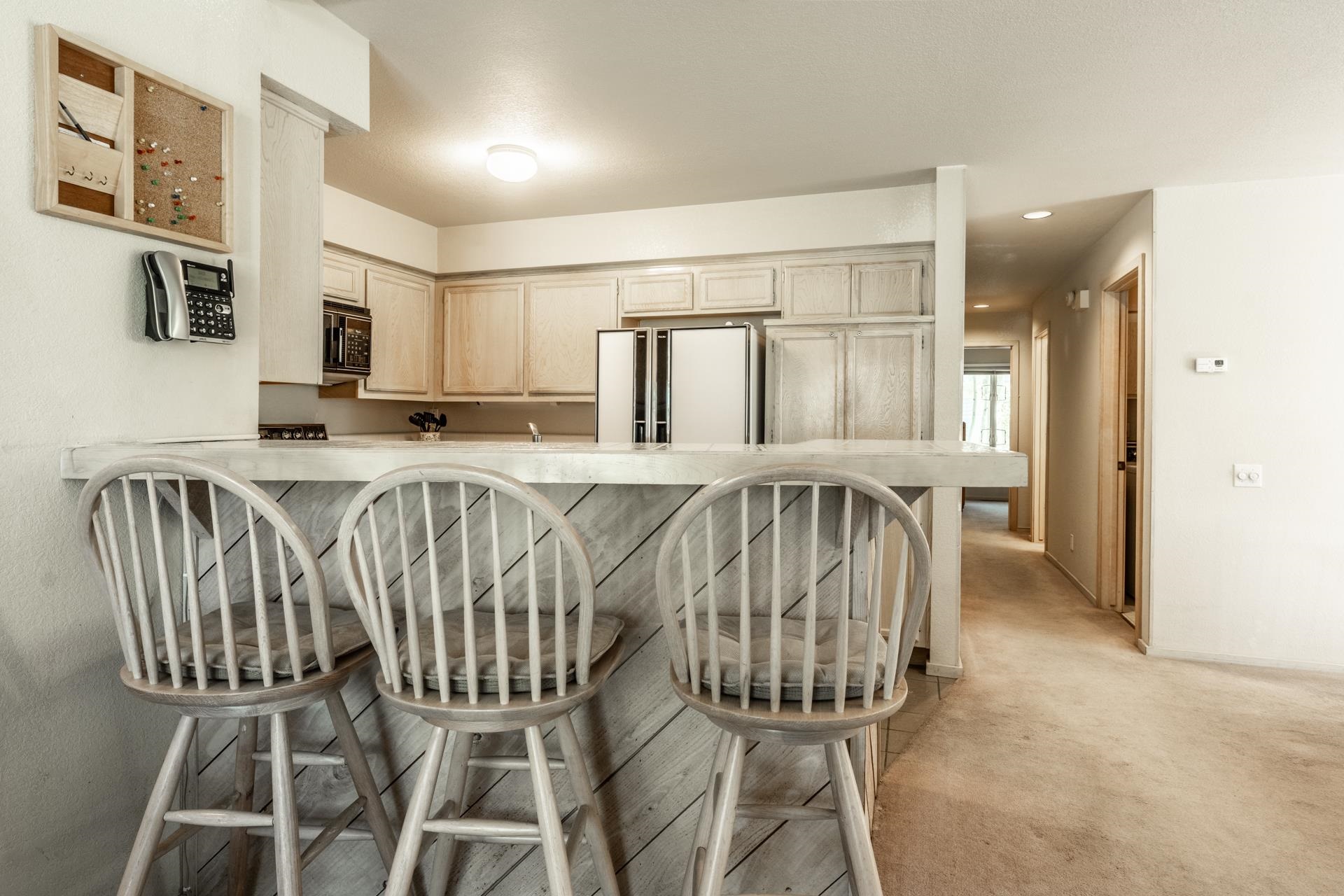 609 Golden Creek Road, Unit 609 Mammoth Lakes, CA 93546 - Photo 21 of 42 Kitchen bar seating with a light-toned countertop, wood-finish cabinetry, and stainless steel appliances