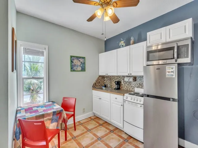 a kitchen with stainless steel appliances a refrigerator a stove a sink cabinets and dining table