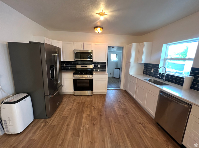 545 23rd Street Ogden, UT 84401 - Photo 3 of 28 Kitchen with wood-finish flooring, white cabinetry, and stainless steel appliances