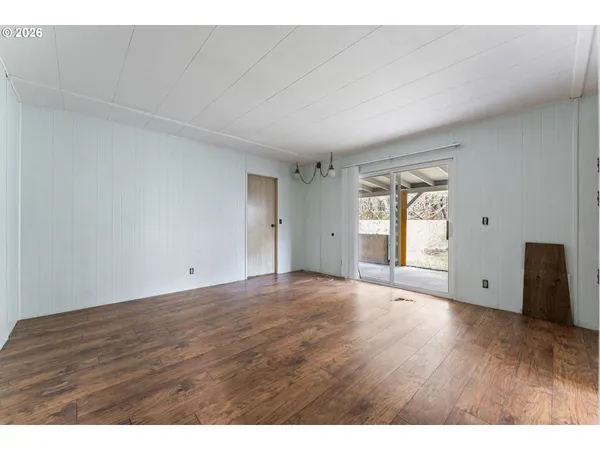 a view of an empty room with wooden floor and window