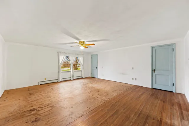 an empty room with wooden floor and window