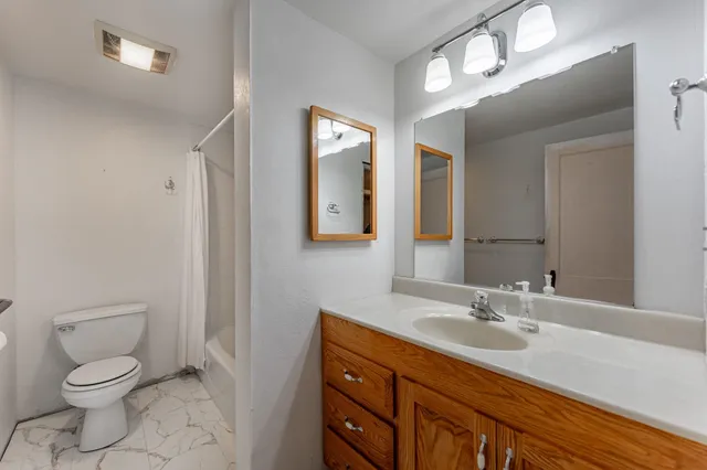 a bathroom with a granite countertop sink mirror vanity and toilet