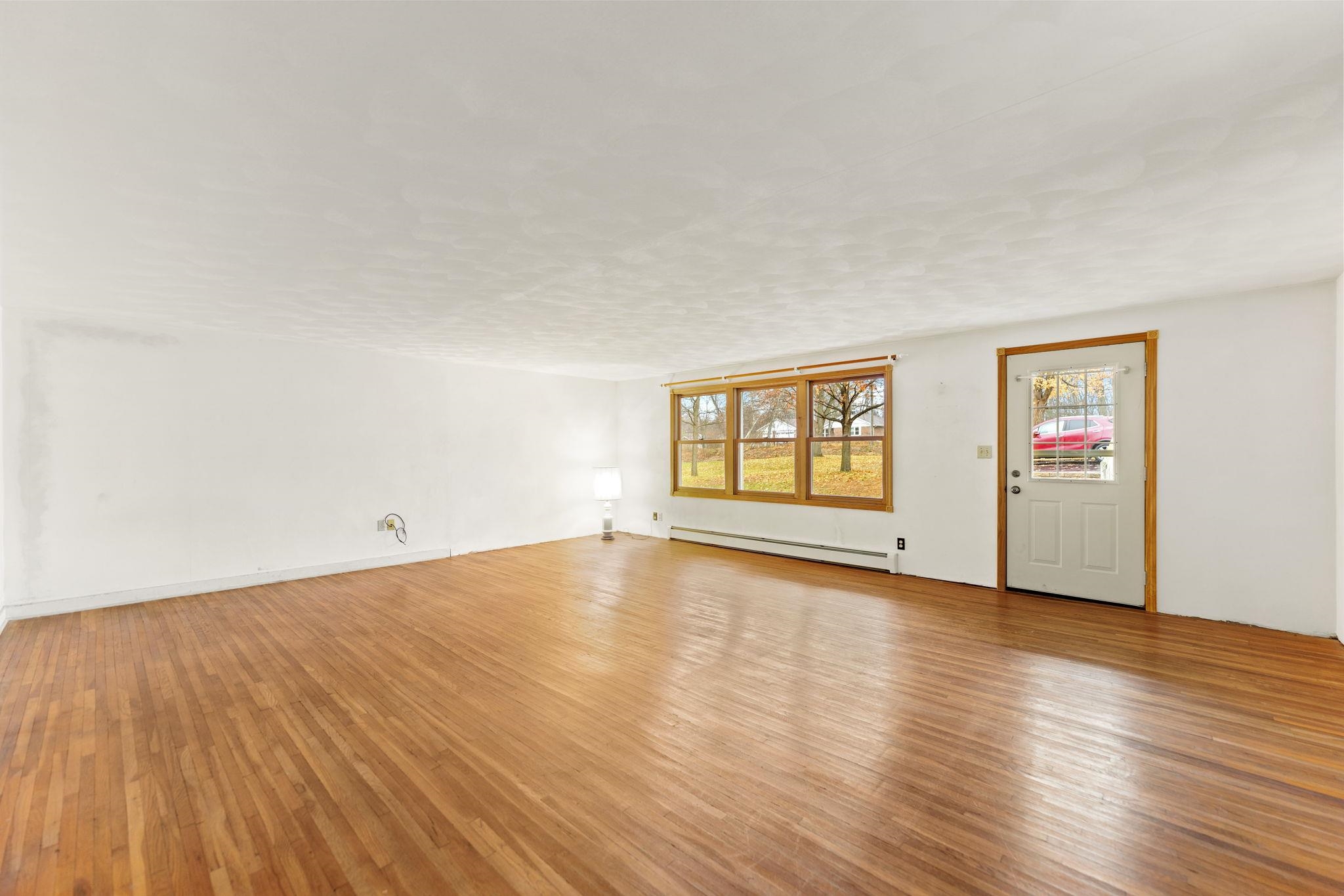 739 Elgin Street Cherry Valley, IL 61016 - Photo 3 of 41 a view of an empty room with wooden floor and a window
