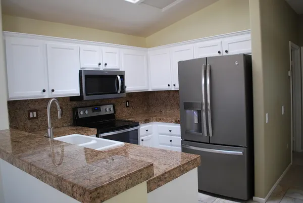 a kitchen with stainless steel appliances granite countertop a refrigerator a stove a microwave and a sink