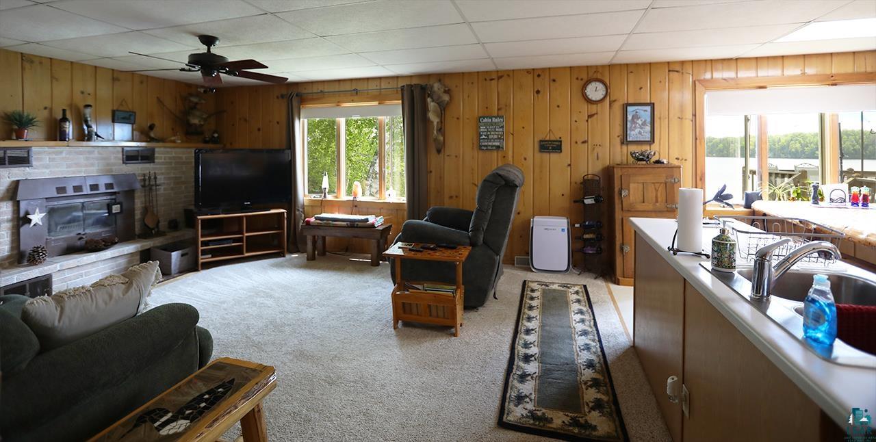 1198 West Mink Road Cotton, MN 55724 - Photo 4 of 23 Living area with light colored carpet, ceiling fan, and wood walls