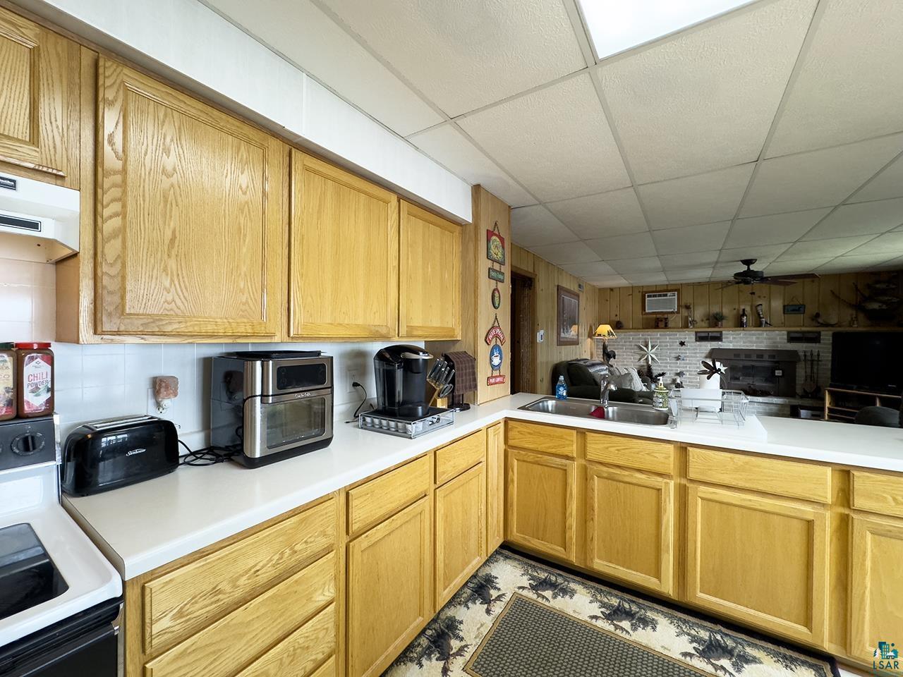 1198 West Mink Road Cotton, MN 55724 - Photo 6 of 23 Kitchen featuring stove, a paneled ceiling, tasteful backsplash, light countertops, and exhaust hood