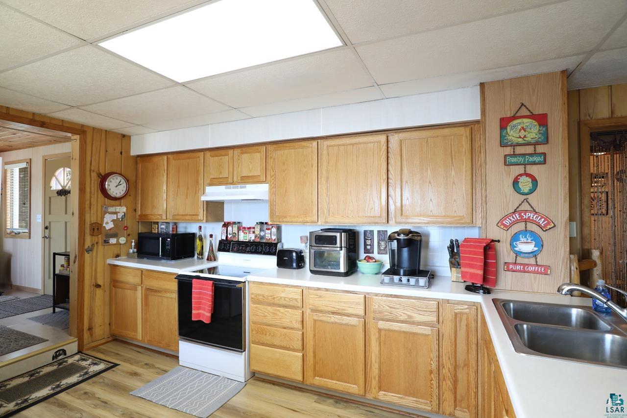 1198 West Mink Road Cotton, MN 55724 - Photo 7 of 23 Kitchen with white appliances, under cabinet range hood, light countertops, a drop ceiling, and brown cabinetry