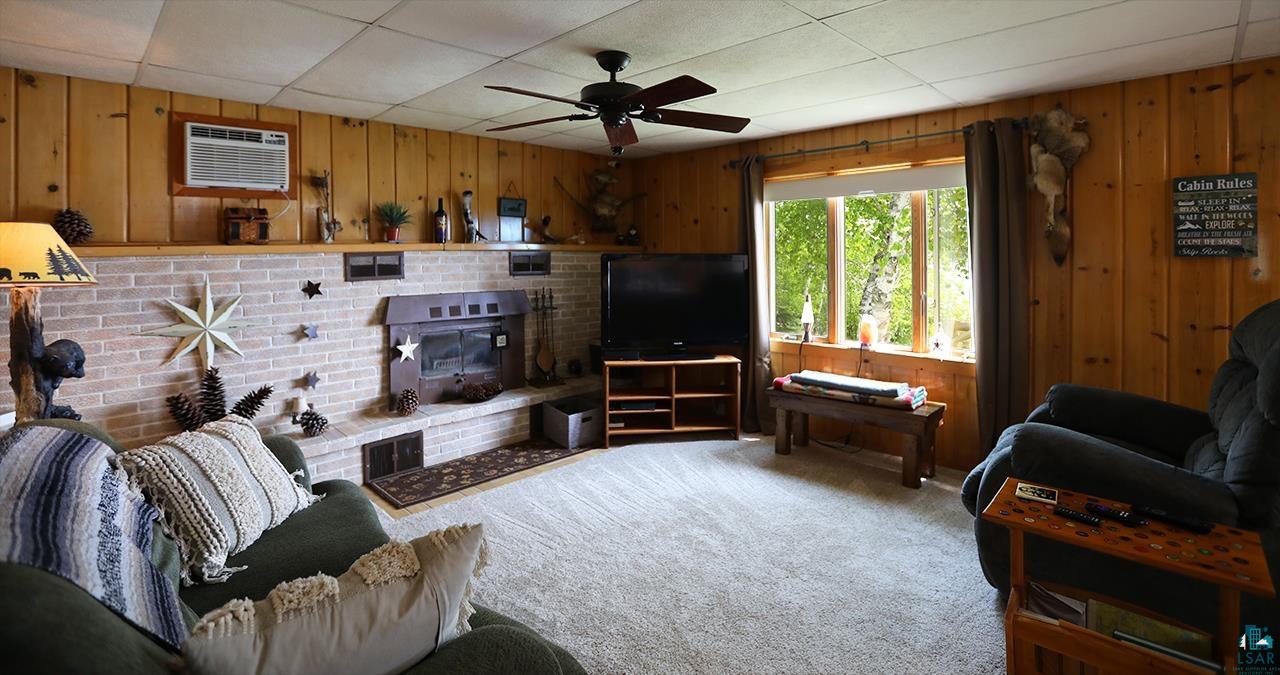 1198 West Mink Road Cotton, MN 55724 - Photo 9 of 23 Living room with wooden walls, a wall mounted air conditioner, carpet, a ceiling fan, and a paneled ceiling