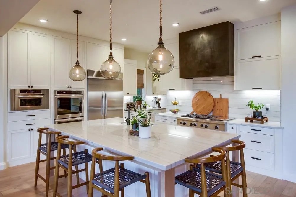 15497 Tanner Ridge Road San Diego, CA 92127 - Photo 3 of 48 a kitchen with stainless steel appliances a dining table chairs and stove top oven