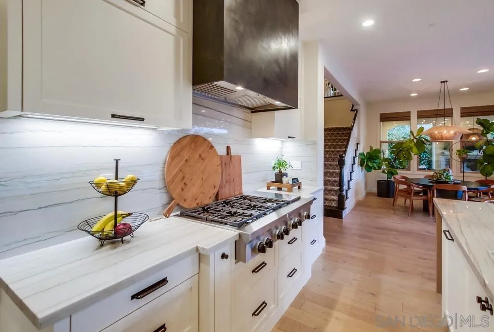 15497 Tanner Ridge Road San Diego, CA 92127 - Photo 5 of 48 a kitchen with stainless steel appliances kitchen island granite countertop a stove a sink a refrigerator and a dining table with wooden floor