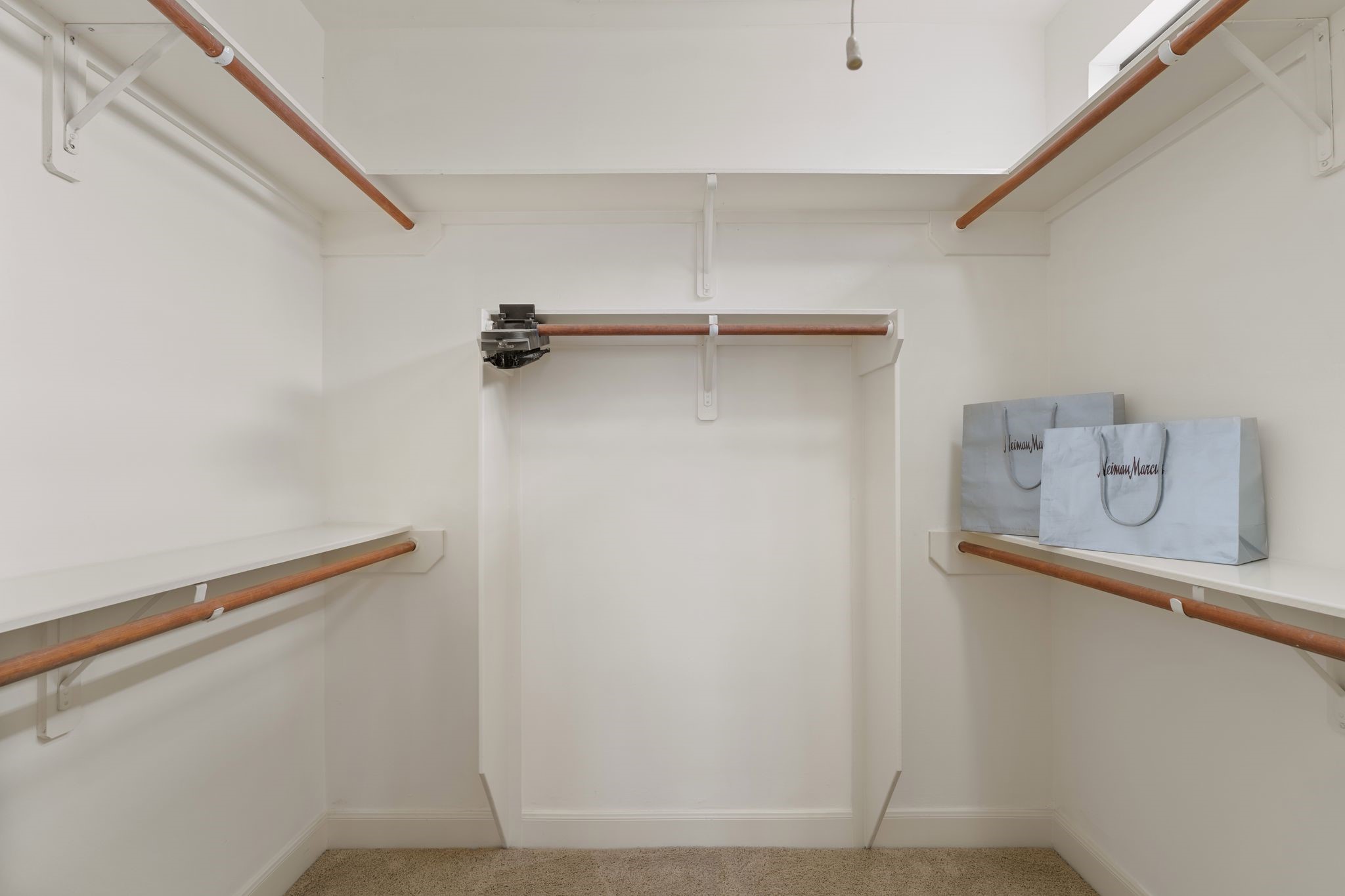121 Roy Street Houston, TX 77007 - Photo 20 of 29 This photo shows a spacious walk-in closet with multiple hanging rods and shelves. It's well-lit with a ceiling light and natural light from upper windows.