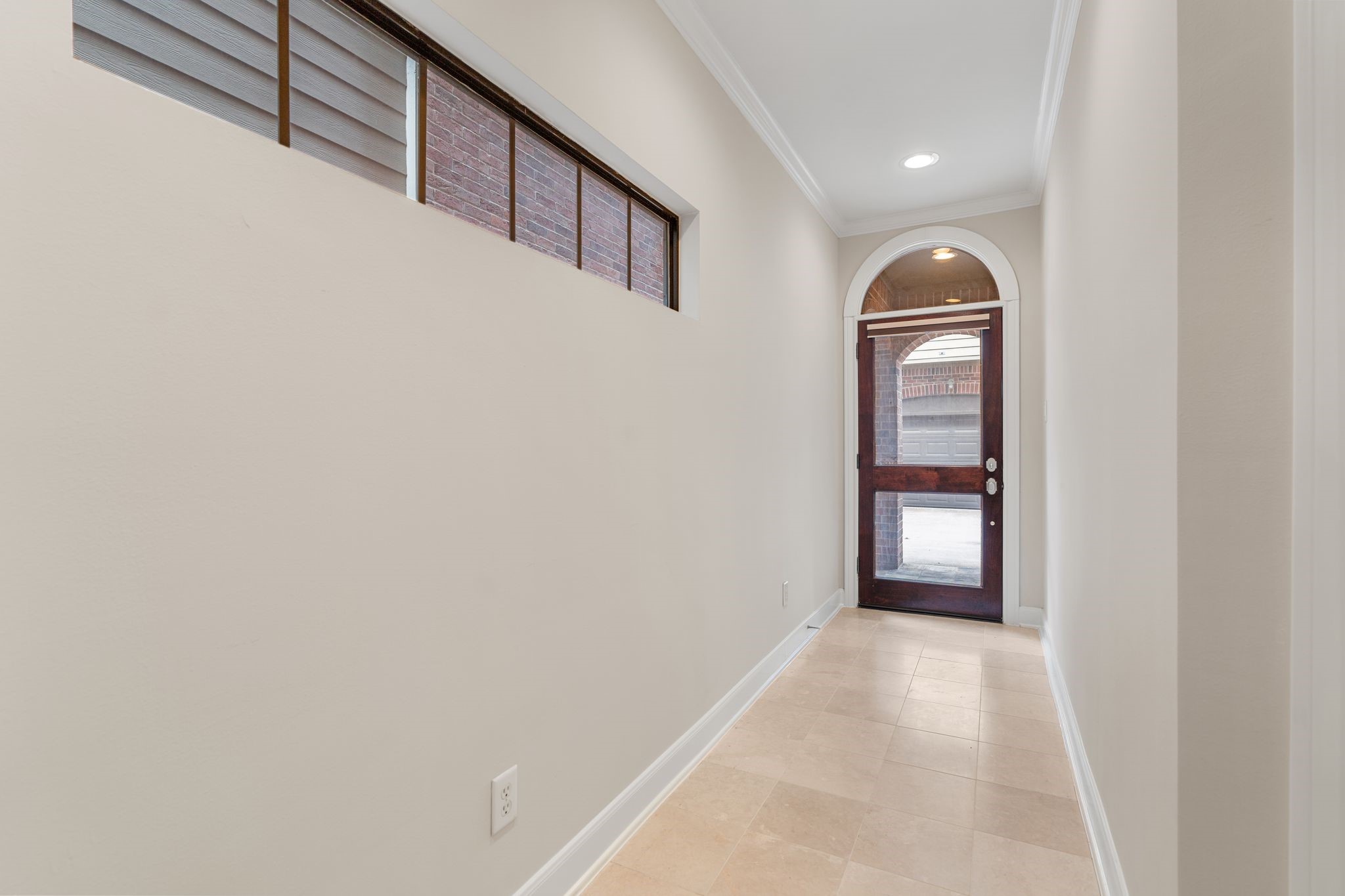 121 Roy Street Houston, TX 77007 - Photo 6 of 29 Bright entry hallway with a modern, arched wood door and upper sidelights, featuring neutral tiles and recessed lighting, leading to an exterior view.