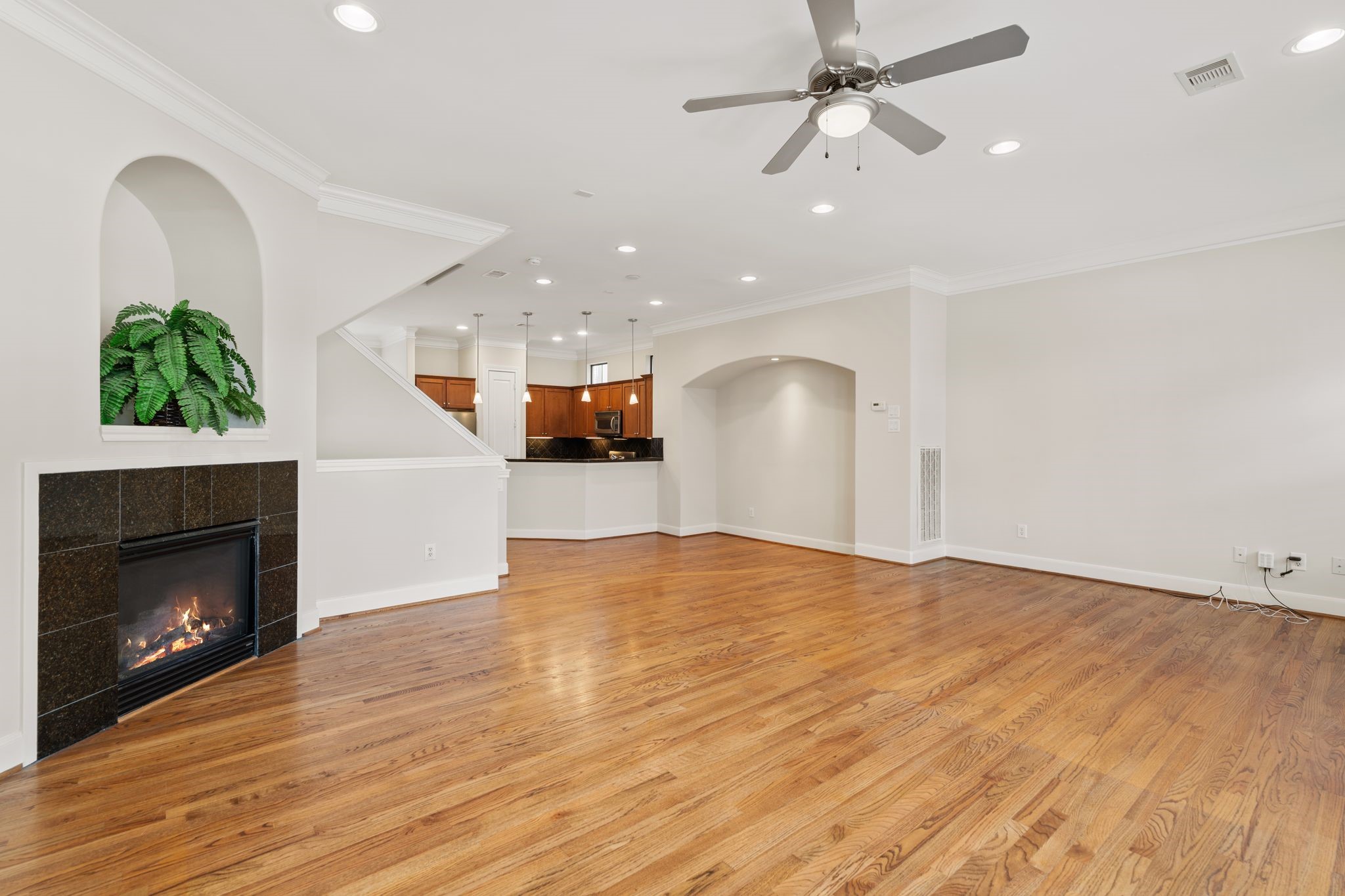 121 Roy Street Houston, TX 77007 - Photo 7 of 29 This inviting living space features hardwood floors, a cozy fireplace, recessed lighting, and a ceiling fan. The open layout leads into a modern kitchen with warm cabinetry, perfect for entertaining.