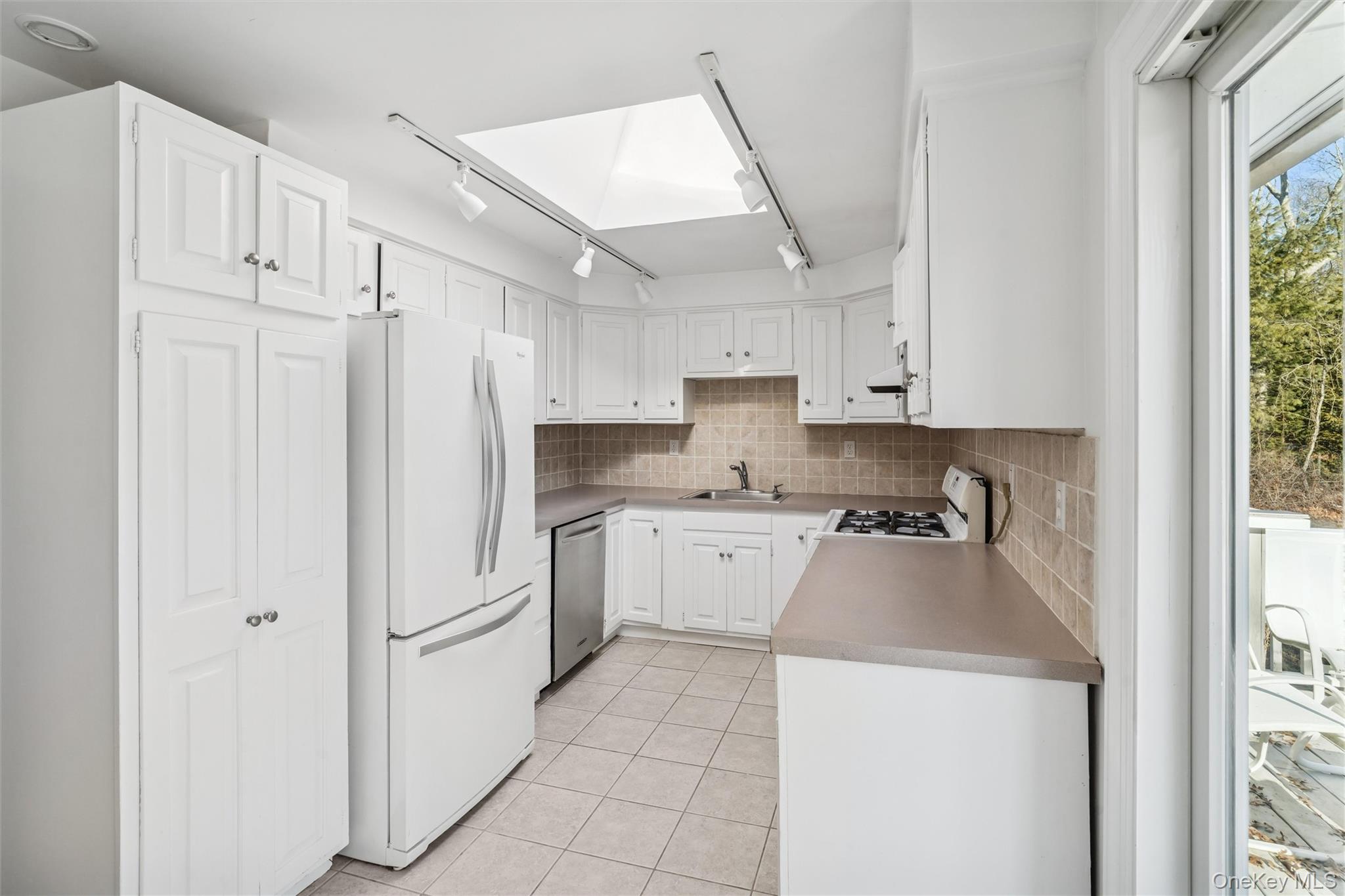58 Old Depot Road Quogue, NY 11959 - Photo 9 of 28 a kitchen with white cabinets and white appliances