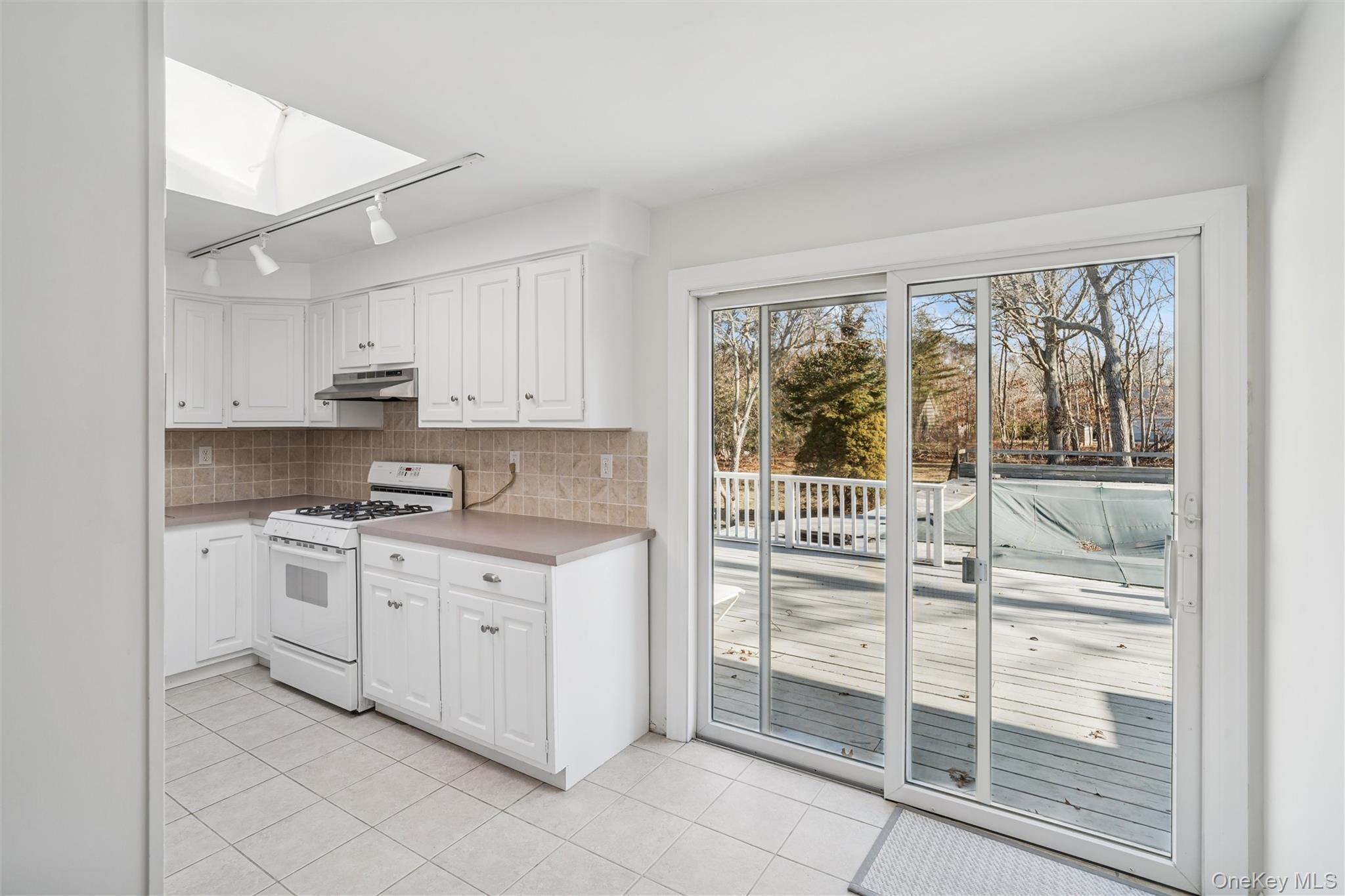58 Old Depot Road Quogue, NY 11959 - Photo 10 of 28 a kitchen with stainless steel appliances granite countertop a stove and white cabinets