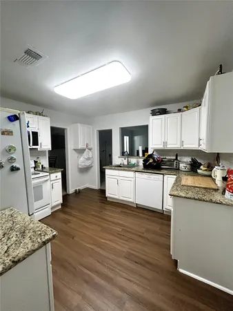 a kitchen with granite countertop a stove top oven and cabinets