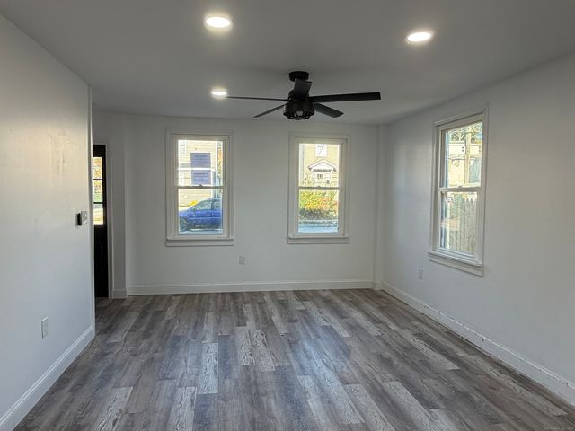 a view of empty room with wooden floor and fan
