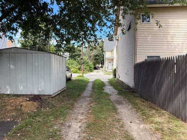 a view of a backyard with large trees and wooden fence