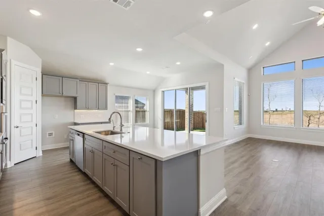 a kitchen with stainless steel appliances granite countertop a sink and wooden floors