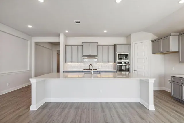 a large kitchen with stainless steel appliances granite countertop a white cabinets and wooden floors