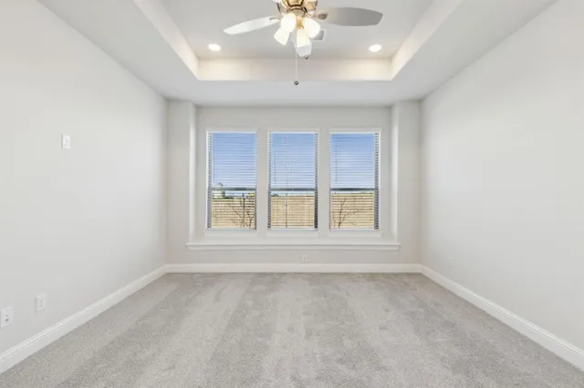 an empty room with a chandelier fan and windows