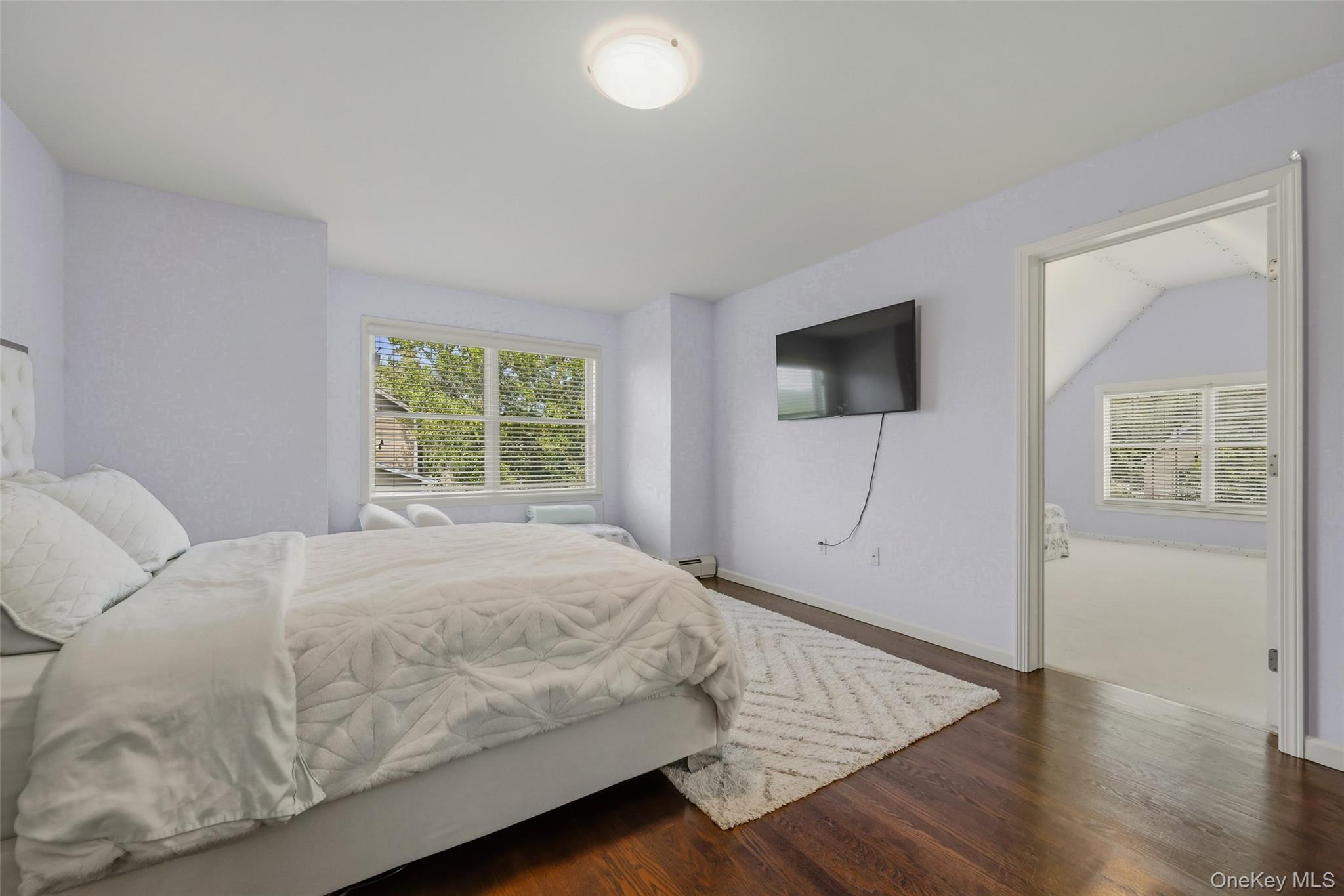 51 Meriwether Trail Congers, NY 10920 - Photo 30 of 50 Spacious room with dark wood-finish flooring, a large window with blinds, and an open doorway leading to an additional space with sloped ceilings and a window