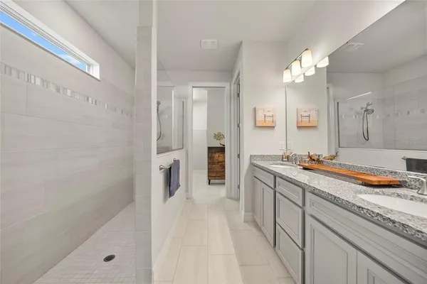 a spacious bathroom with a double vanity sink a large mirror and shower