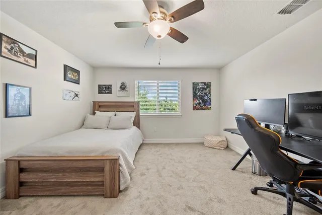 a bedroom with a bed a computer on a desk and chair