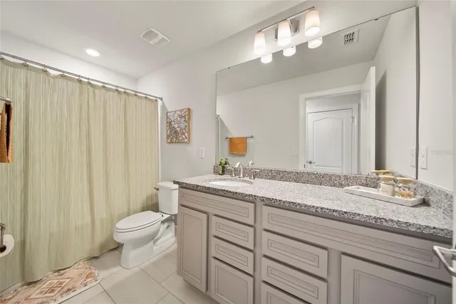 a bathroom with a granite countertop sink a toilet and a mirror