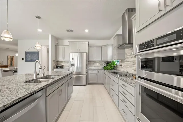 a large kitchen with granite countertop lots of counter space and stainless steel appliances