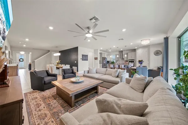a living room with furniture kitchen view and a chandelier
