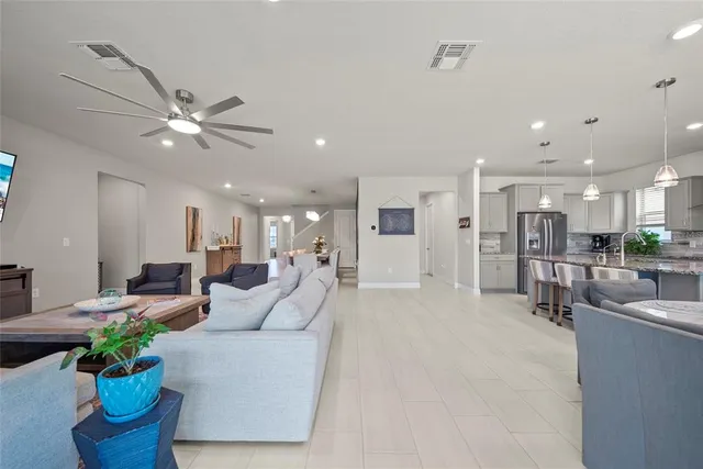 a living room with furniture potted plant and kitchen view