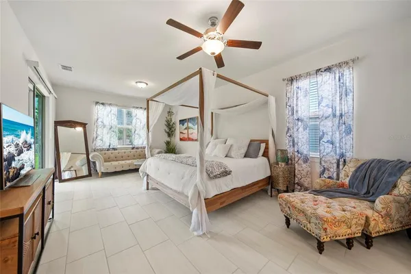a spacious bedroom with a bed a couch and a chandelier