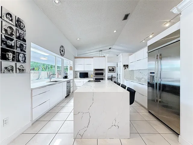 a large white kitchen with a large window and stainless steel appliances
