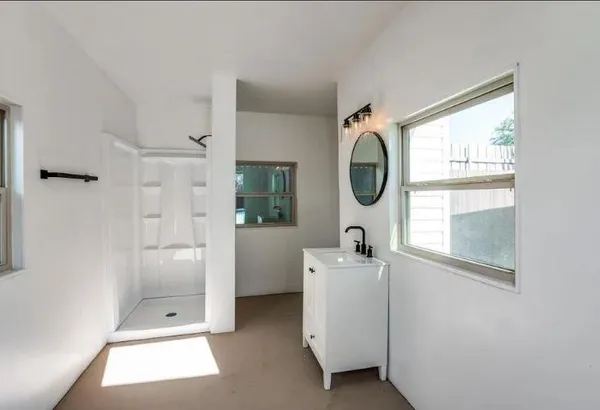 a bathroom with a granite countertop shower a mirror and a window