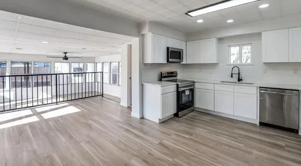 a kitchen with stainless steel appliances granite countertop a stove top oven a sink dishwasher and white cabinets with wooden floor