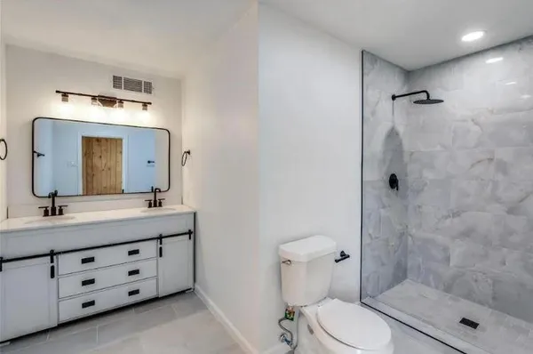a bathroom with a double vanity sink toilet mirror and shower