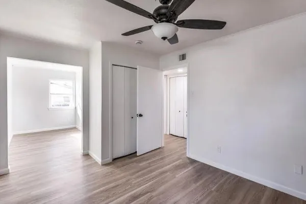 a view of an empty room with a window and wooden floor