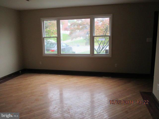 1045 Grovehill Road Baltimore, MD 21227 - Photo 4 of 27 a view of an empty room with wooden floor and a window