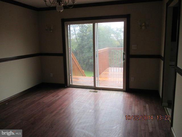 1045 Grovehill Road Baltimore, MD 21227 - Photo 6 of 27 a view of an empty room with wooden floor and a window