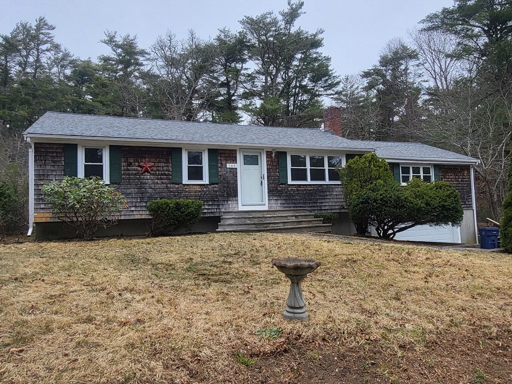 a front view of house with yard and trees in the background