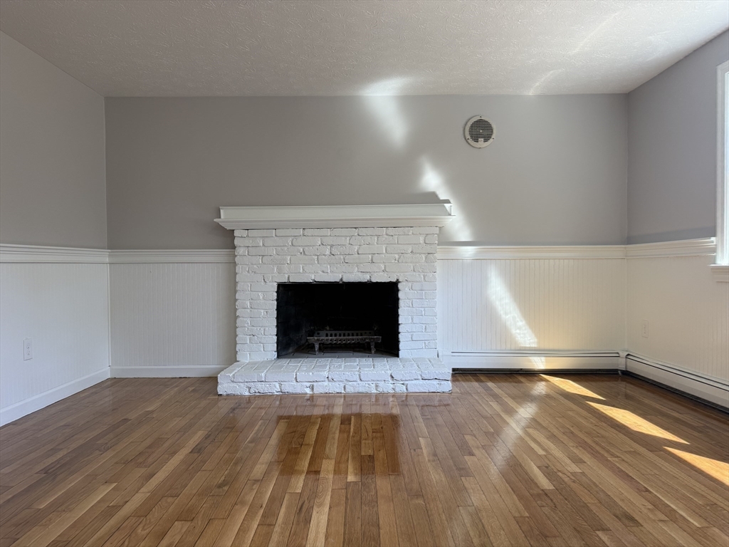 165 Hedges Pond Road Plymouth, MA 02360 - Photo 14 of 20 a view of an empty room with wooden floor a fireplace and a window