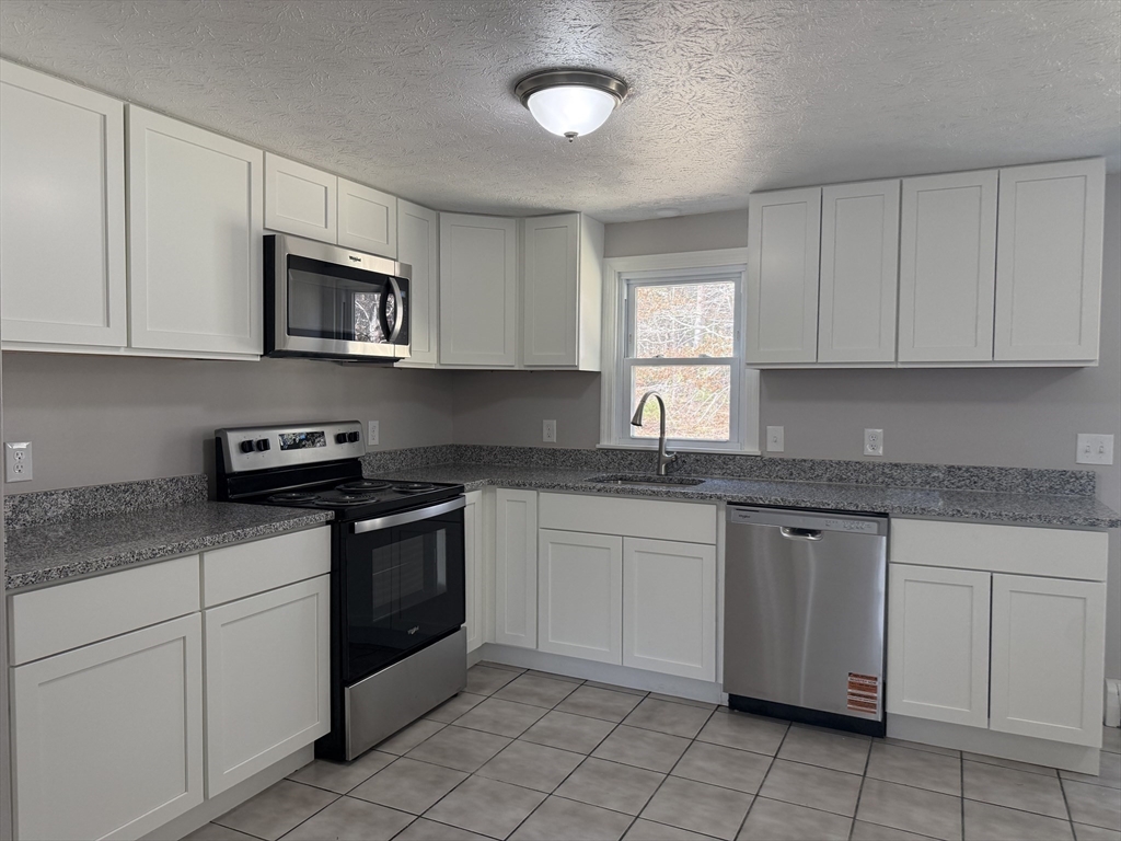 165 Hedges Pond Road Plymouth, MA 02360 - Photo 7 of 20 a kitchen with white cabinets granite counter tops and a stove