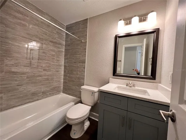 a bathroom with a toilet sink vanity tub and mirror