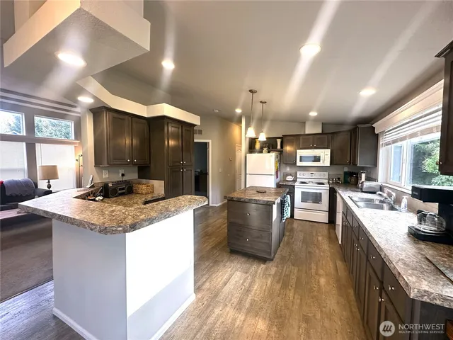 a kitchen with stainless steel appliances granite countertop wooden cabinets a sink dishwasher and a stove with wooden floor